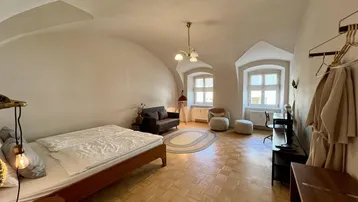 Geräumiges Schlafzimmer mit Parkettboden, Gewölbedecke und Arbeitsbereich.
