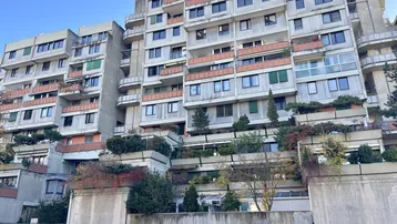 Mehrstöckiges Wohngebäude mit vielen Balkonen und begrünten Terrassen in moderner Architektur.