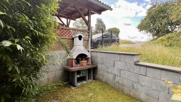 Gemütlicher Grillplatz im Garten mit gemauerter Feuerstelle und Sitzgelegenheit.