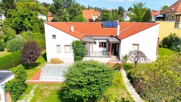 Luftaufnahme des Hauses mit großem Garten, überdachtem Pool und Photovoltaikanlage auf dem Dach.