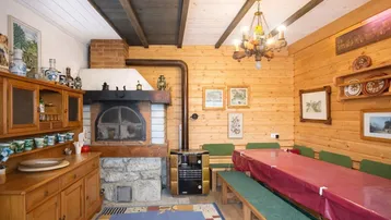 Rustikaler Essbereich mit großem Kamin, Holzwänden und langen Holzbänken.