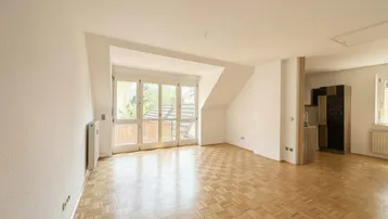 Helles Zimmer mit Parkettboden, Dachschrägen und Zugang zu einem französischen Balkon.