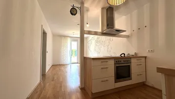 Offene Küche mit Holzboden, Dunstabzugshaube und Blick in den angrenzenden Wohnbereich.