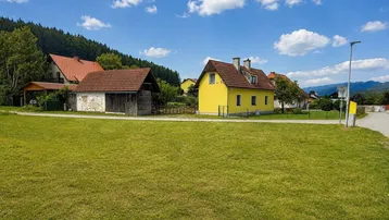 Weitläufige Ansicht des gelben Hauses mit Nebengebäuden und ländlicher Umgebung.