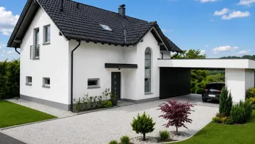 Modernes Einfamilienhaus mit weißer Fassade, schwarzem Dach und integriertem Carport auf einem gepflegten Grundstück.
