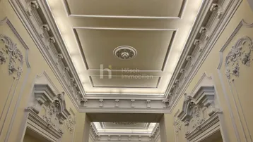 Eindrucksvoller Eingangsbereich mit aufwendigen Stuckverzierungen an Decke und Wänden, beleuchtet durch indirektes Licht.