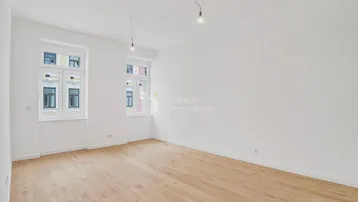Heller, leerer Raum mit Holzboden und zwei Fenstern, bereit zur individuellen Gestaltung.