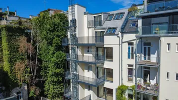 Modernes Gebäude mit mehreren Balkonen und einer externen Treppenanlage an der Fassade.