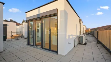 Geräumige Dachterrasse mit Fliesenboden und einem weiten Blick auf die umliegende Landschaft.