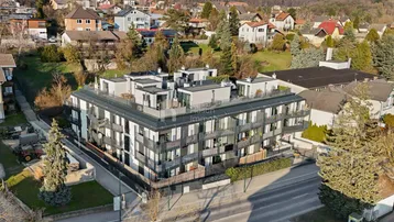 Luftaufnahme des modernen Wohnkomplexes in einer grünen Umgebung mit umliegenden Häusern und viel Natur.