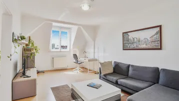 Helles Wohnzimmer im Dachgeschoss mit Schrägfenster, Holzboden und moderner Einrichtung.