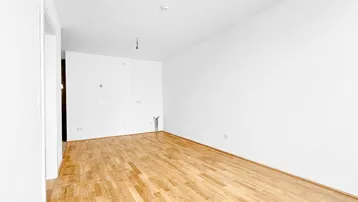 Heller, unmöblierter Raum mit Parkettboden und weißen Wänden, bereit zur individuellen Gestaltung.