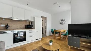 Heller offener Wohn-Essbereich mit integrierter Küche, Holzboden und modernen Möbeln.