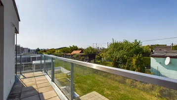 Geräumiger Balkon mit Fliesenboden und Glasgeländer, bietet Weitblick.