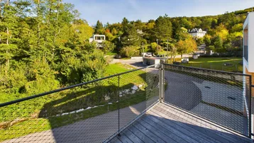 Balkon mit Holzboden und Metallgeländer bietet einen weiten Blick in die grüne Landschaft.