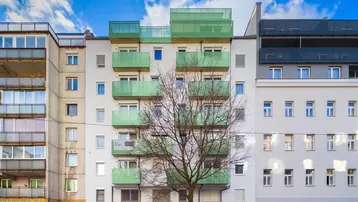 Moderne Wohnhausfassade mit hellgrünen Balkonen und blauer Himmelskulisse in urbaner Umgebung.