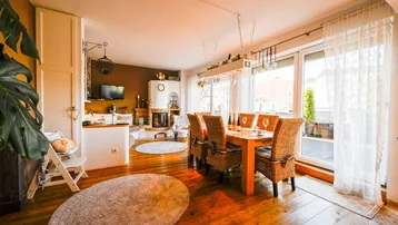 Helles Wohn- und Esszimmer mit Holzboden, Kamin und Zugang zur Terrasse.