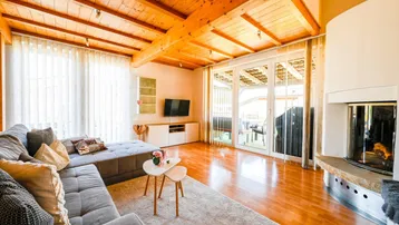 Helles Wohnzimmer mit Holzbalkendecke, Parkettboden und Zugang zur Terrasse.