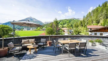 Große Holzterrasse mit Sitzgelegenheiten und weitem Blick auf die umliegende Berglandschaft.