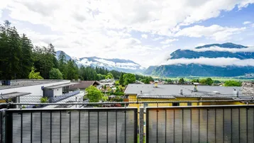 Balkon mit Gittergeländer und weitem Blick auf die umliegende Berglandschaft und das Tal.