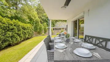 Überdachte Terrasse mit Esstisch und Blick auf den gepflegten Garten.