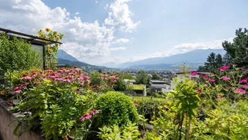 Malerischer Gartenbereich mit bunten Blumen und weitem Blick auf die umliegende Berglandschaft.