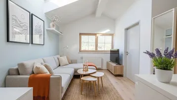 Helles Wohnzimmer im Dachgeschoss mit Dachfenster, Holzboden und modernem Sofa.
