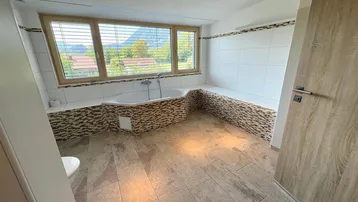 Helles Badezimmer mit Eckbadewanne, Fenster und Bergblick, ausgestattet mit modernen Fliesen.