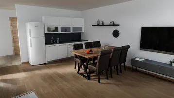 Heller offener Wohn-Essbereich mit integrierter Küche, Holzboden und modernem Esstisch.
