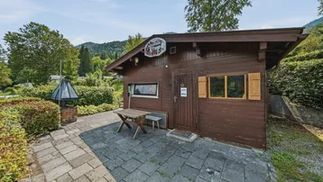 Kleines Holzhaus mit gepflasterter Terrasse und Sitzgelegenheiten im Freien.