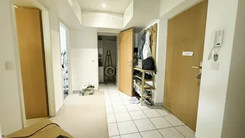 Langer Flur mit Fliesenboden und Garderobe, der zu verschiedenen Räumen führt.