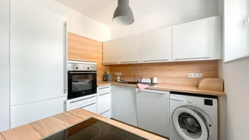Moderne Einbauküche mit weißen Fronten, Holzarbeitsplatte und integrierten Geräten.