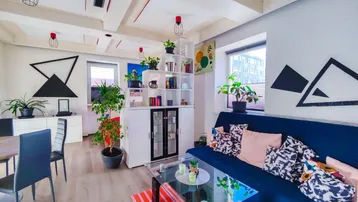 Helles Wohn- und Esszimmer mit Holzbalkendecke, modernen Möbeln und Pflanzen.