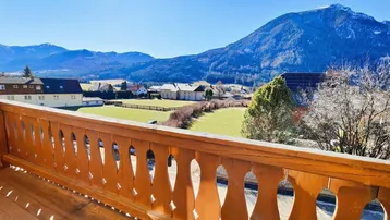 Geräumiger Holzbalkon mit traditionellem Geländer und Panoramablick auf die Berge.