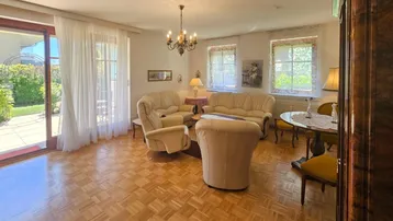 Gemütliches Wohnzimmer mit Parkettboden, beigen Sofas und Zugang zur Terrasse und zum Garten.