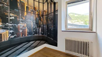Schlafzimmer mit großer Stadtsilhouetten-Tapete und Fenster mit Blick ins Grüne.
