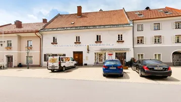 Historisches Gebäude mit Bäckerei und Café im Erdgeschoss an einem sonnigen Stadtplatz.