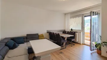 Heller Wohn- und Essbereich mit modernem Sofa, Esstisch und Zugang zum Balkon.