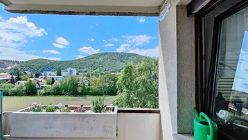 Weitläufiger Ausblick vom Balkon auf grüne Hügel, Bäume und die umliegende Landschaft.