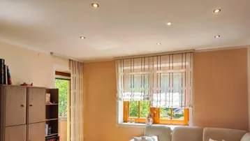 Helles Wohnzimmer mit gemütlichem Sofa, Einbaustrahlern und Zugang zu einem Balkon.