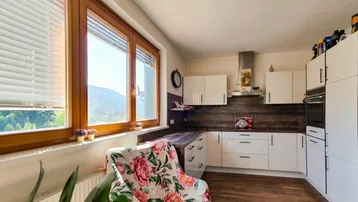 Helle Küche mit weißen Schränken, Holzboden und einem schönen Bergblick durch große Fenster.