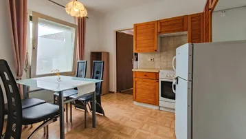 Helle Küche mit Essbereich, Holzschränken, Parkettboden und Blick nach draußen.