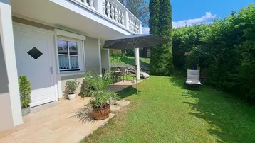 Gepflegter Gartenbereich mit Terrasse, Liegestühlen und Sonnenschirm, ideal zum Entspannen im Freien.