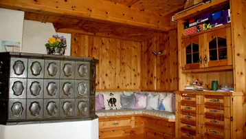 Rustikales Wohnzimmer mit traditionellem Kachelofen, Holztäfelung und gemütlicher Sitzecke.