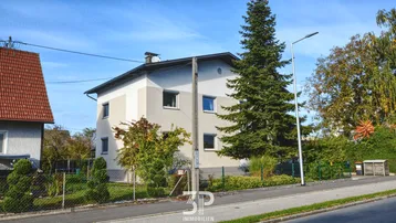 Freistehendes Einfamilienhaus mit gepflegtem Garten und blauer Himmel.