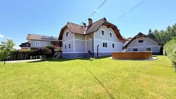 Großer Gartenbereich mit Rasenfläche und einem runden Aufstellpool vor dem Haus.