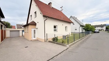 Einfamilienhaus mit Satteldach, Vorgarten und gepflasterter Einfahrt in ruhiger Wohngegend.
