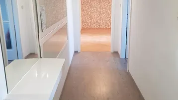 Heller Flur mit Spiegel, Konsole und Garderobe, der zu weiteren Räumen führt.