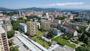 Luftaufnahme der Wohngebäude im städtischen Umfeld mit Blick auf die umliegende Bebauung und Berge im Hintergrund.