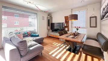 Heller Wohn- und Essbereich mit Holzboden, bequemer Couch und Esstisch, durchflutet von natürlichem Licht.